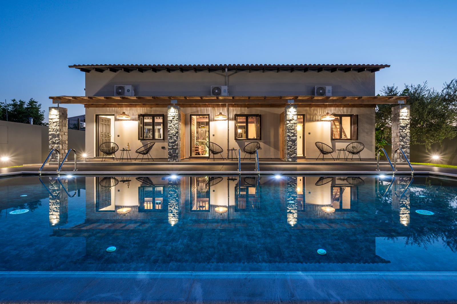 Eightyfour Living at dusk, the three houses lit behind the private pool